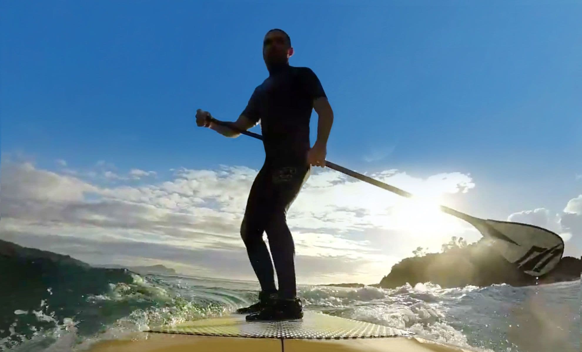 A person standing on a paddleboard in the ocean with waves around.