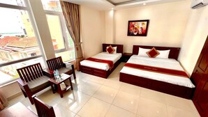 A hotel room with two beds, a dining table, chairs, and a large window with curtains. - Dattravi Hostel (Da Nang)