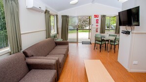 Una habitación con un conjunto de sofá, una mesa de madera y un televisor montado en la pared.