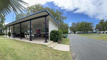 A modern building with a covered patio area, outdoor seating, and a paved walkway.