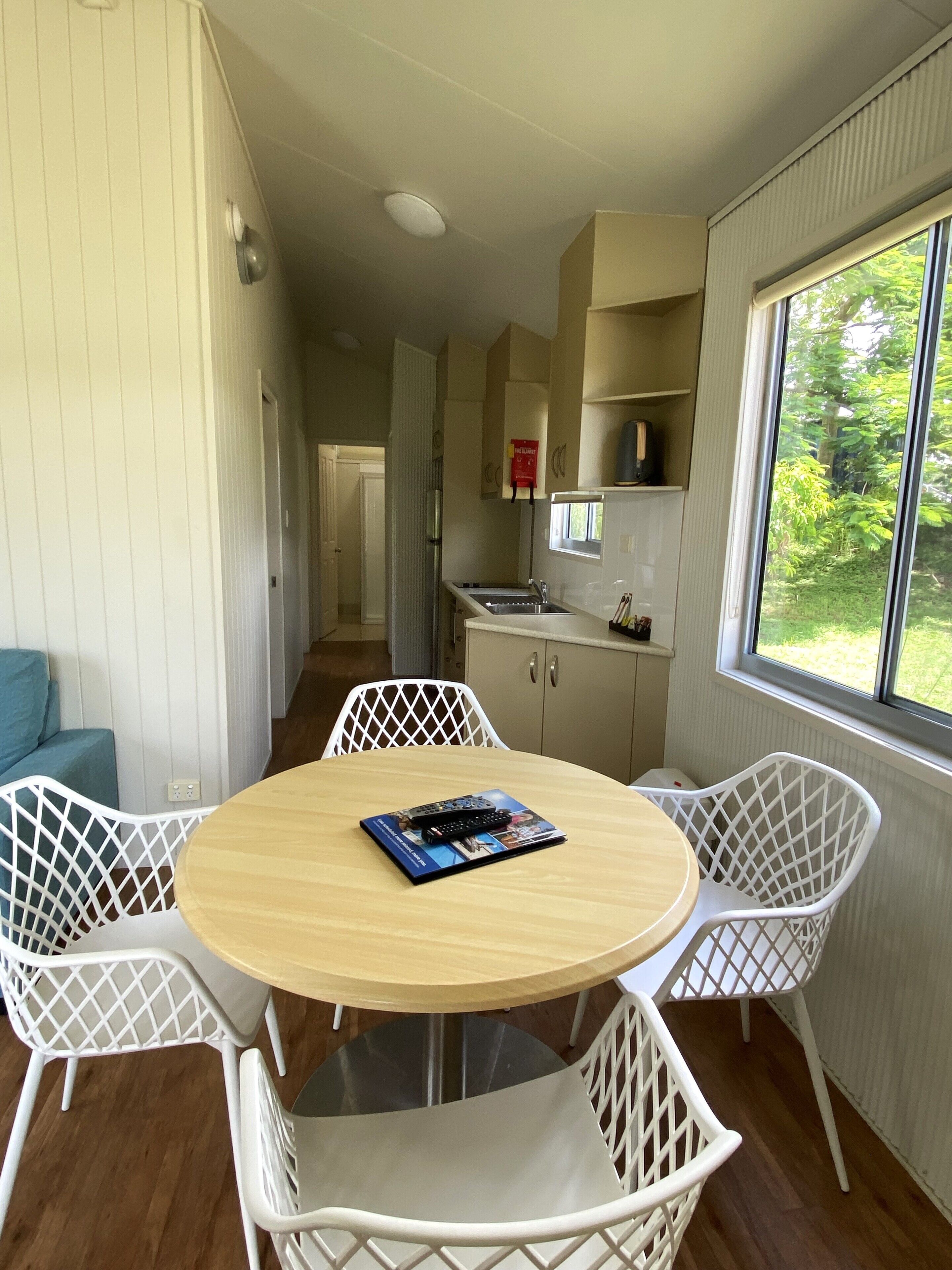 Cocina compacta con lavamanos, armarios y ventana con vistas a zonas verdes.