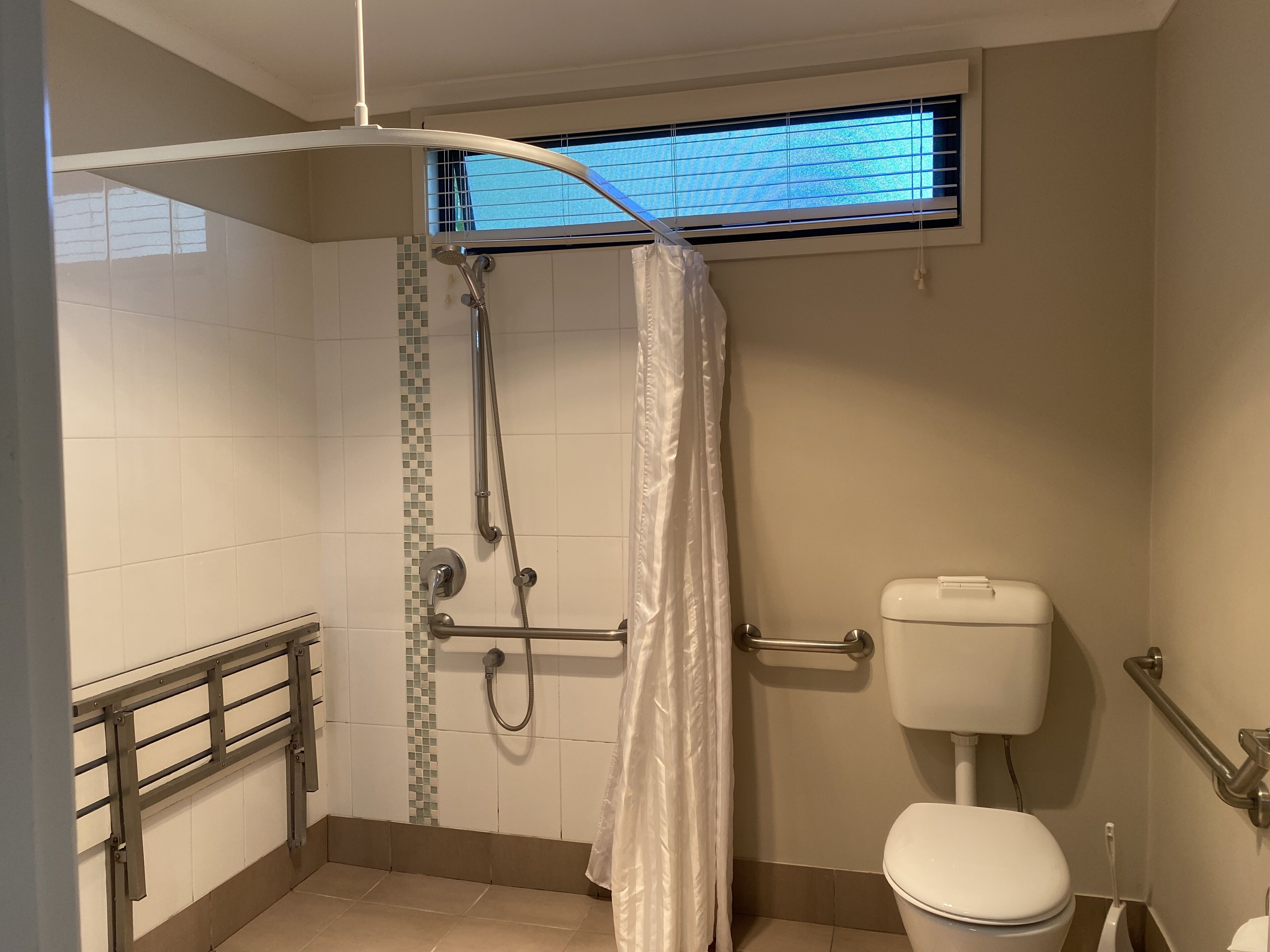 A bathroom with a shower, toilet, and window.