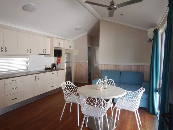 Una cocina moderna con armarios blancos, un refrigerador de acero inoxidable y un comedor con sillas blancas y una mesa redonda.