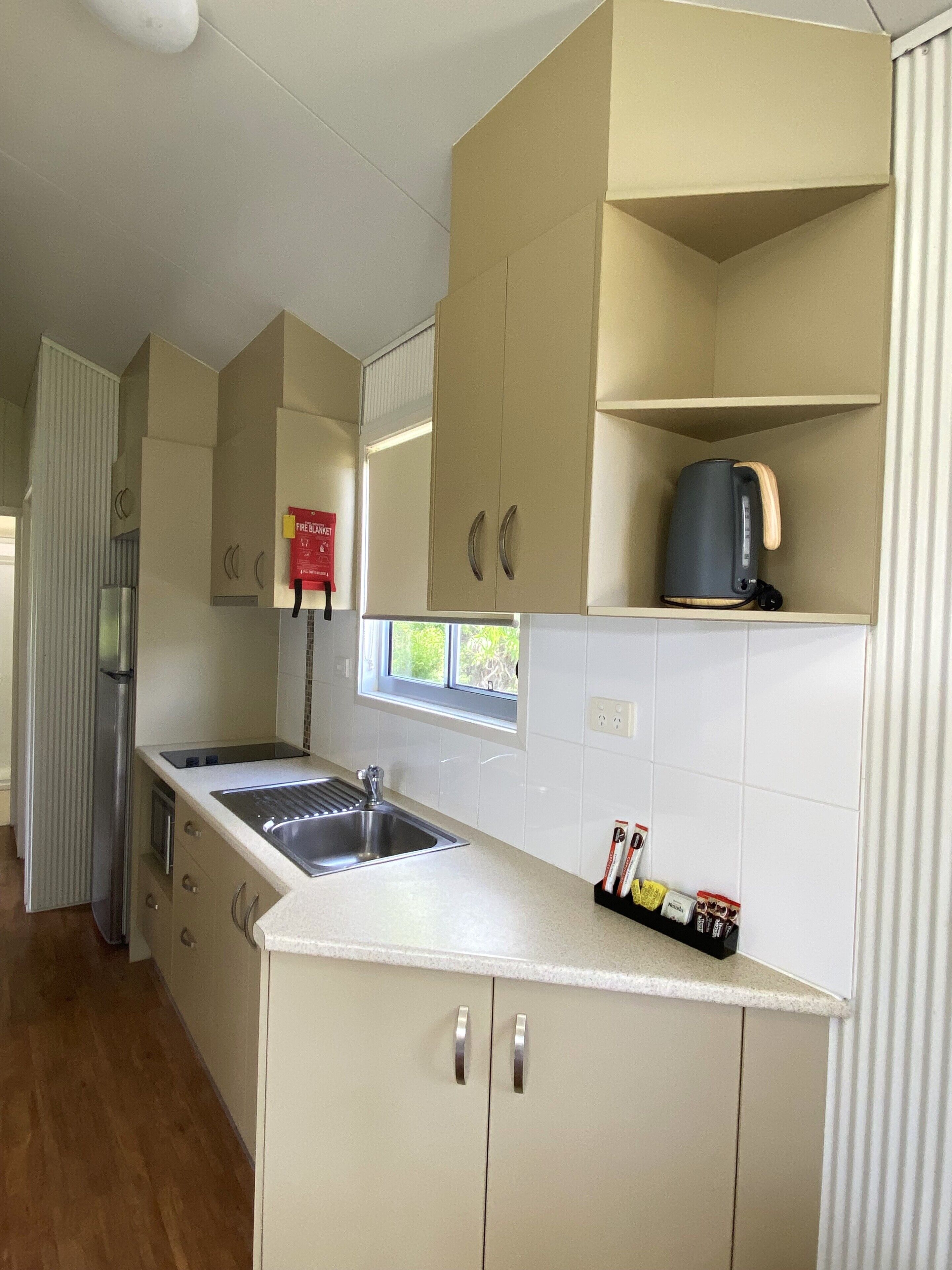 A modern kitchen with a stainless steel sink, a kettle, and a window.