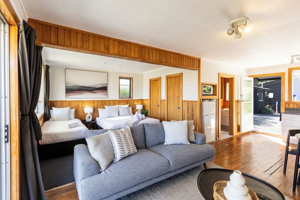 Interior moderno de um veículo recreativo, com sala de estar, quarto e cozinha compacta.