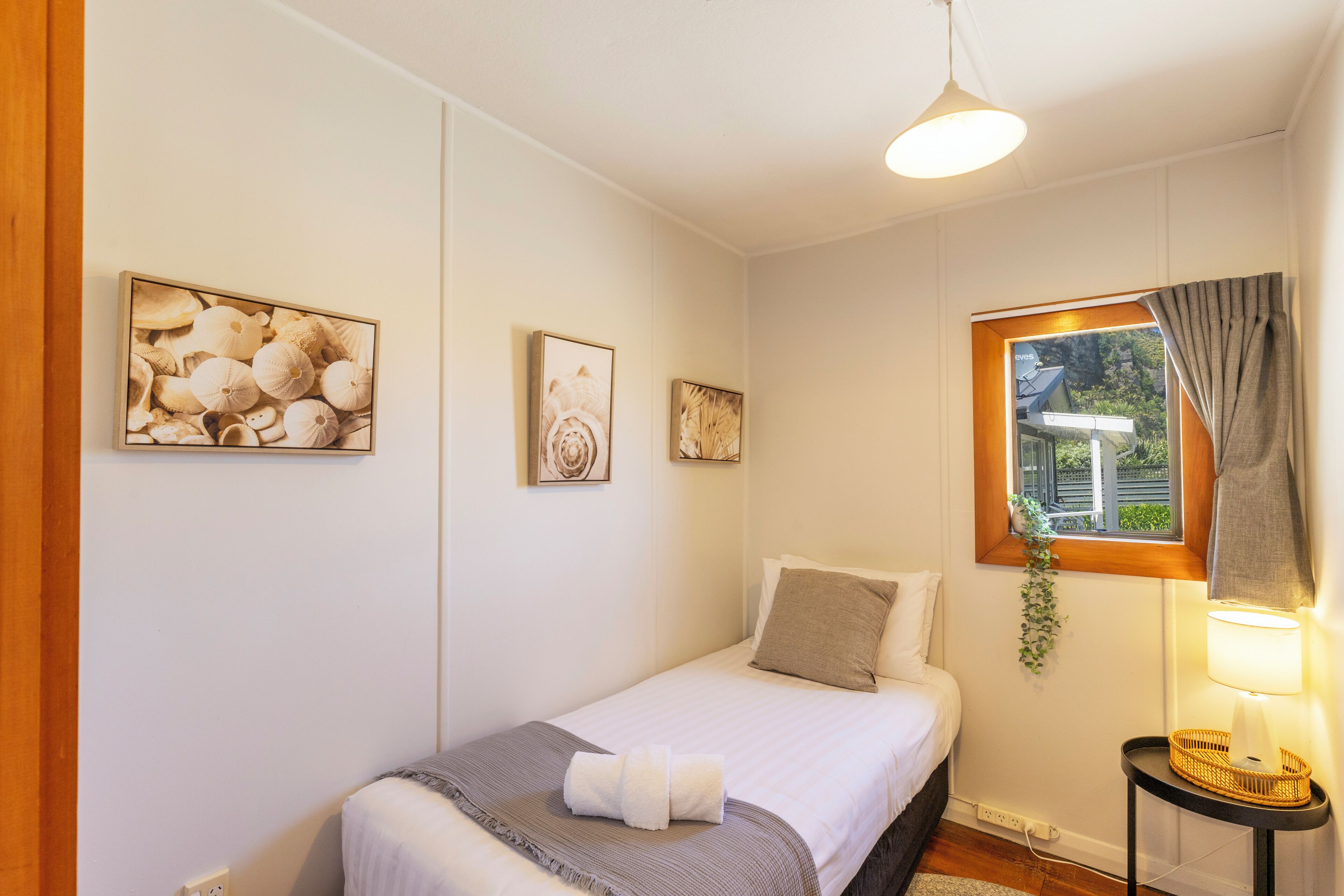 A bedroom with a bed, a bedside table with a lamp, and wall art.