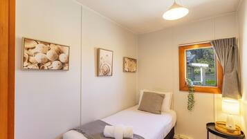 A bedroom with a bed, a bedside table with a lamp, and wall art.