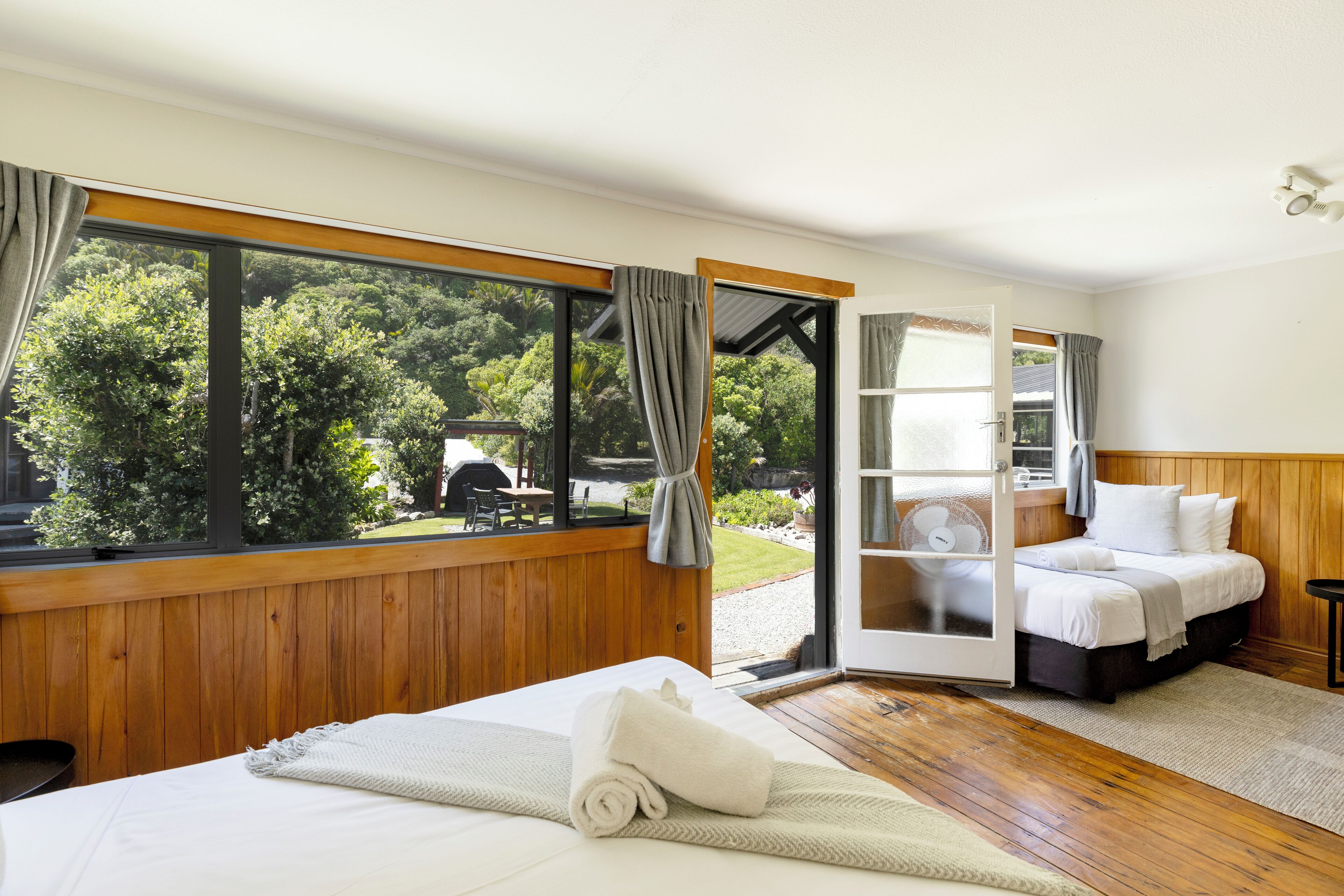 Un dormitorio con un ventanal grande, una cama, una mesita de noche y vistas al exterior.
