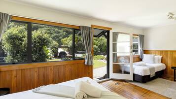 Un dormitorio con un ventanal grande, una cama, una mesita de noche y vistas al exterior.