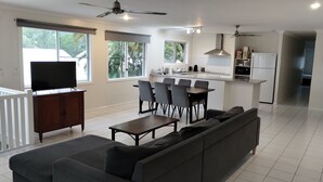 A modern living room with a sofa, TV, dining table, and chairs. - Tully Motel (Tully)