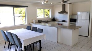 A modern kitchen with a central island, a dining area with a table and chairs, and a refrigerator. - Tully Motel (Tully)