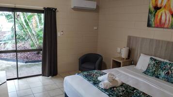 A hotel room with a bed, a chair, a nightstand, and a painting.