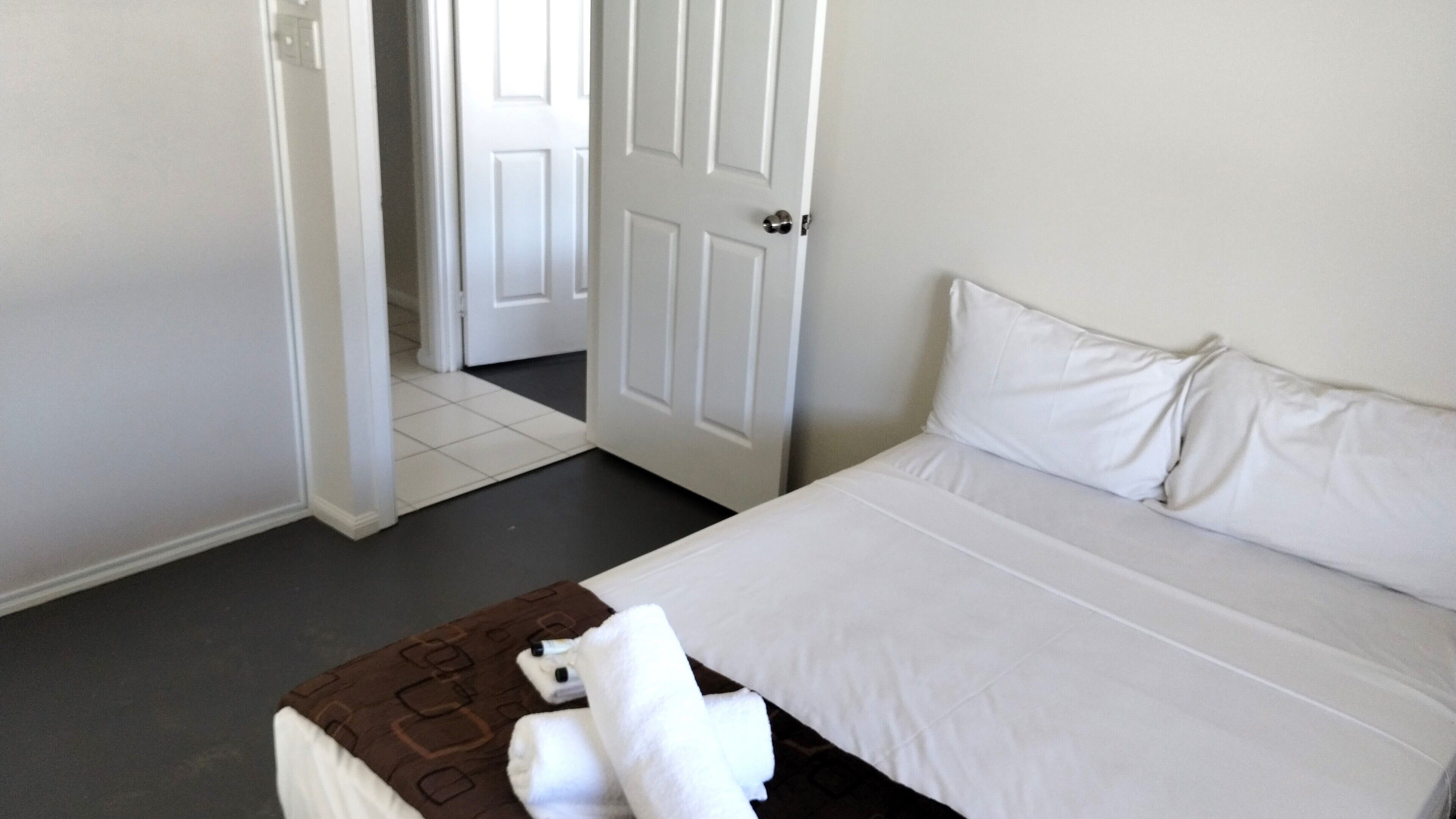 Una camera d'albergo con un letto, una porta e un pavimento piastrellato.