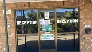 Zona de recepción con un cartel que dice 'Pooraka Motel Inn Adelaide' y un letrero de 'Recepción' sobre la entrada.