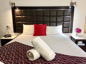 Relax in a stylish room with a large bed, white nightstand, and a lamp.