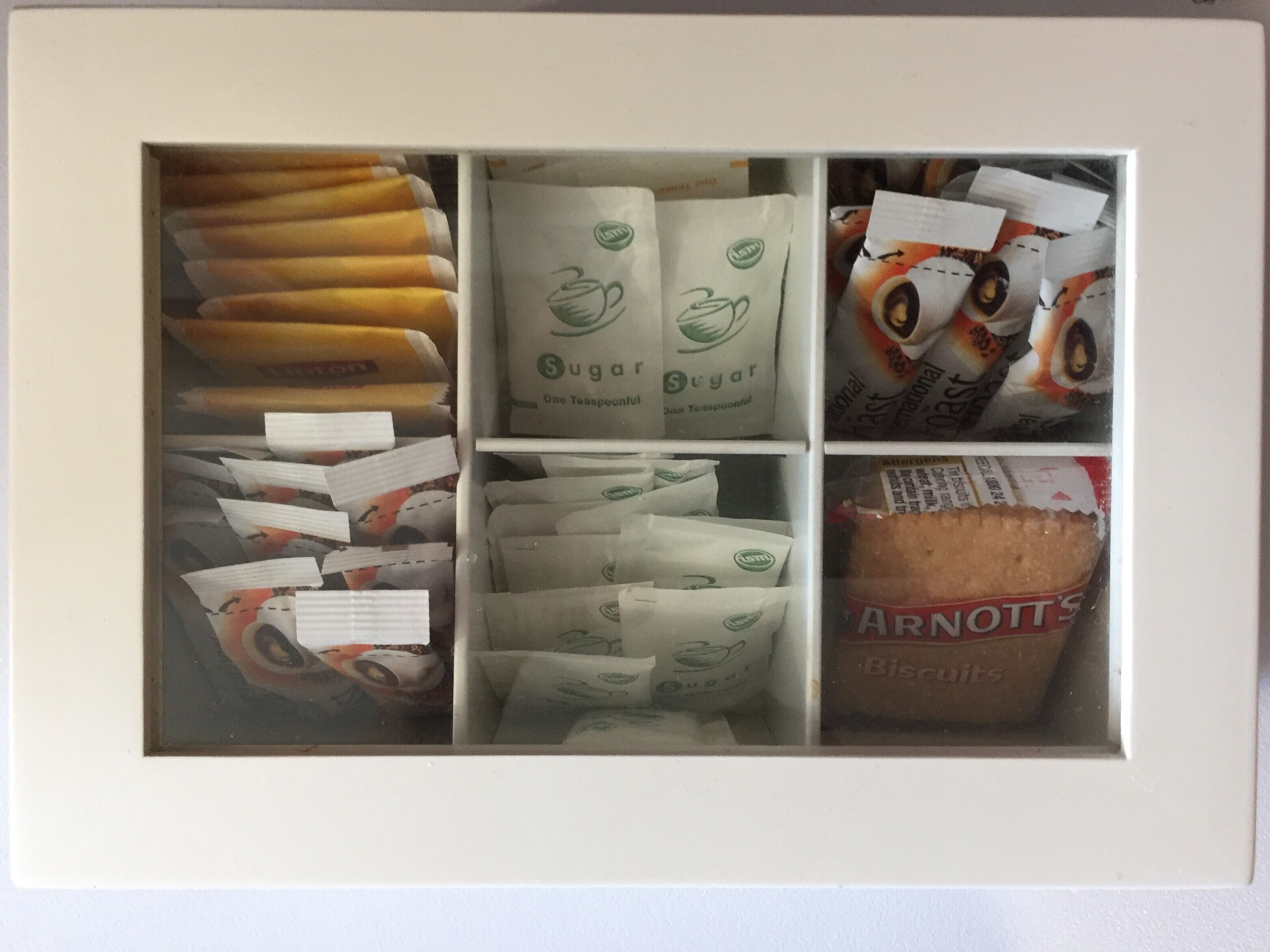 Eine Aufbewahrungsbox mit Zuckerportionen, Keksen und Bananen.