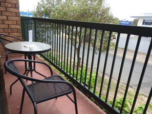 Enjoy a peaceful moment on the balcony with a round table and two chairs, surrounded by lush greenery and city views.