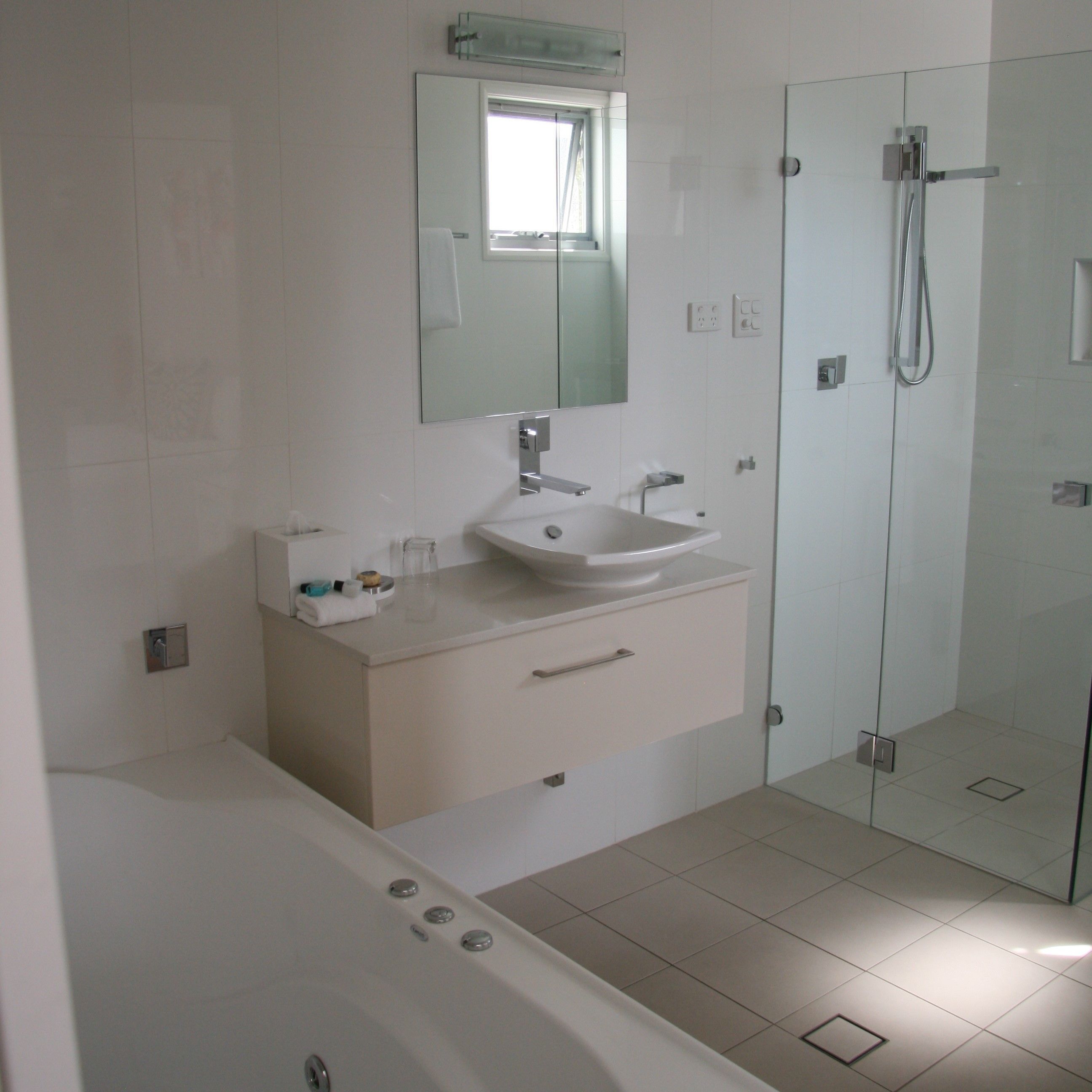 A modern bathroom with a white sink, mirror, and bathtub.