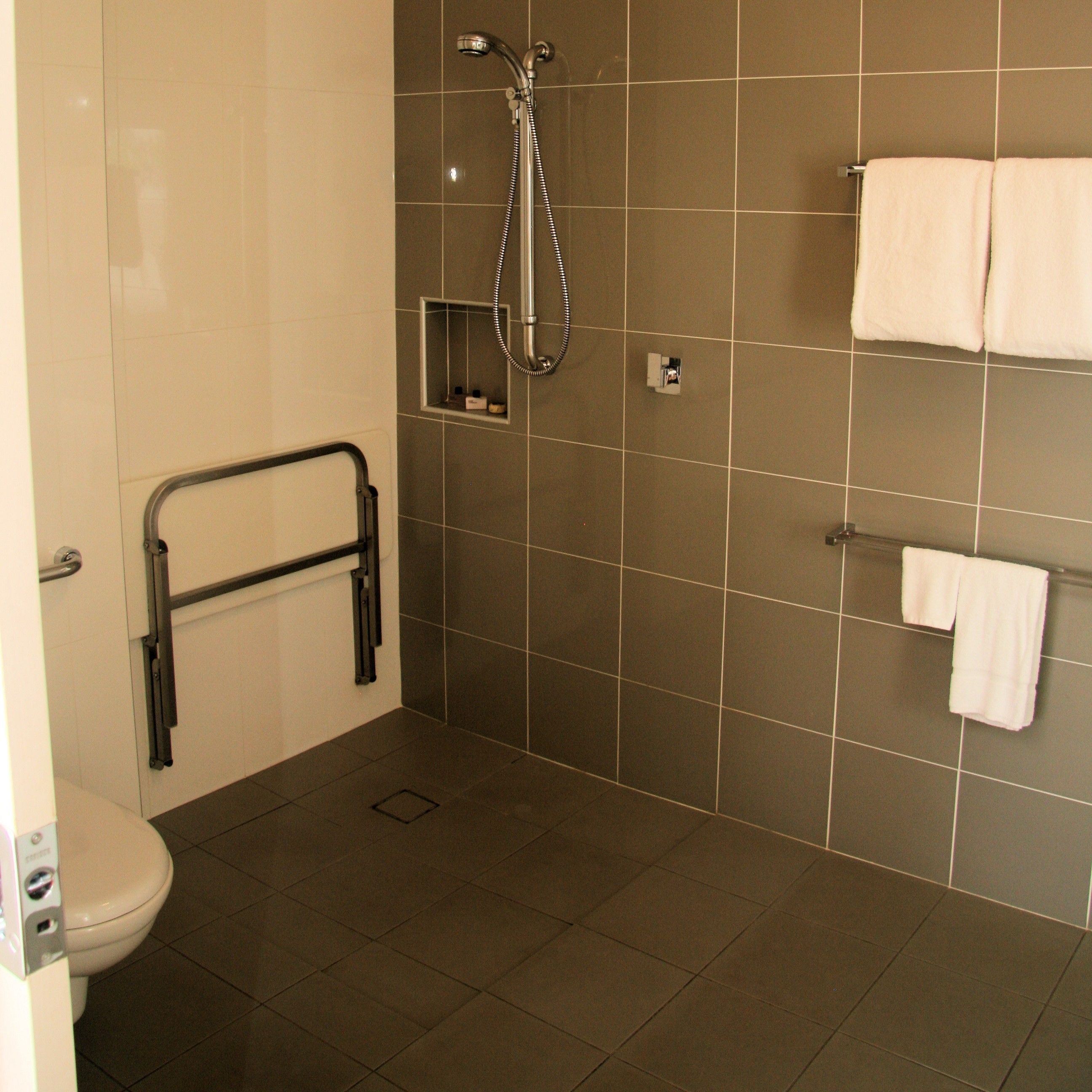 Ett badrum med dusch, toalett och handduksställ.