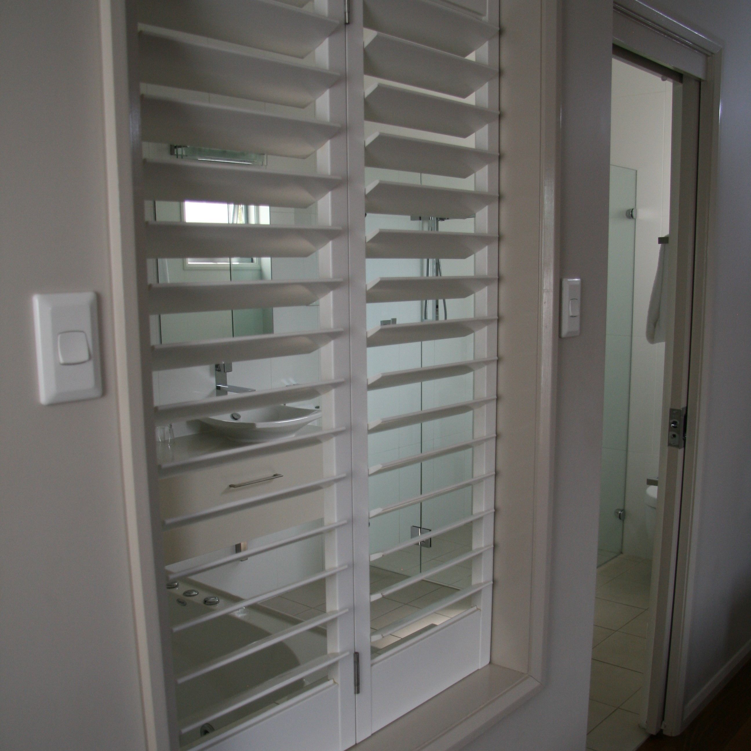 A bathroom with a white vanity, a glass shower enclosure, and a white door.
