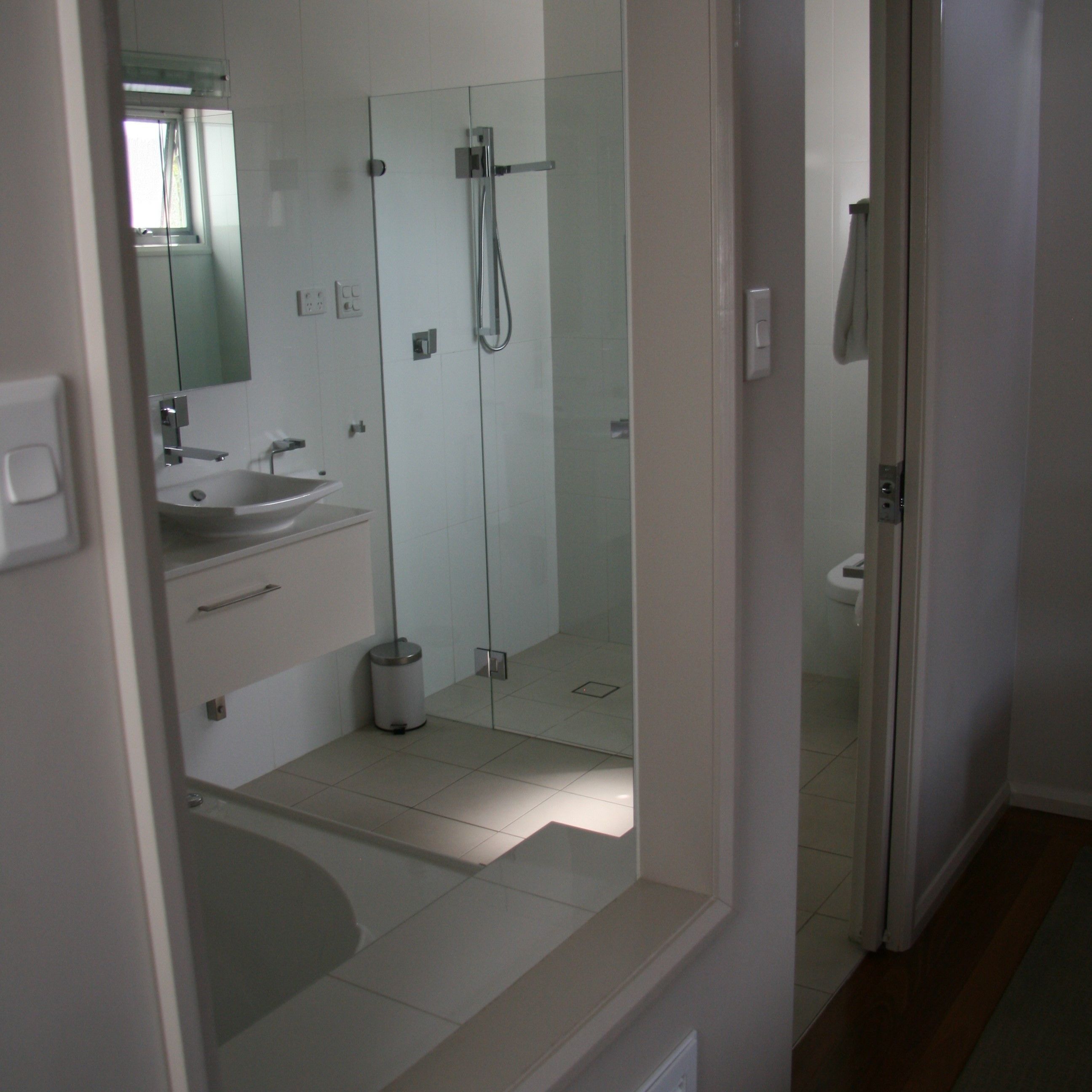 A modern bathroom with a glass shower enclosure, a sink, and a mirror.