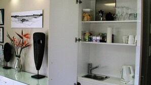 Een moderne keuken met een inbouwspoelbak, koffiezetapparaat en een glazen aanrechtblad.