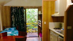 A compact room with a bed, a dining table, and a kitchenette.