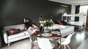 Un soggiorno moderno con un divano, un tavolo da pranzo con sedie, un portatile e una pianta.