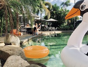 A pool area with a large inflatable swan, a clear pool, and outdoor seating. - Motel Nomad Cairns (Westcourt)