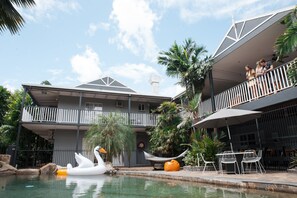 A hotel with a pool, outdoor seating, and a swan float. - Motel Nomad Cairns (Westcourt)