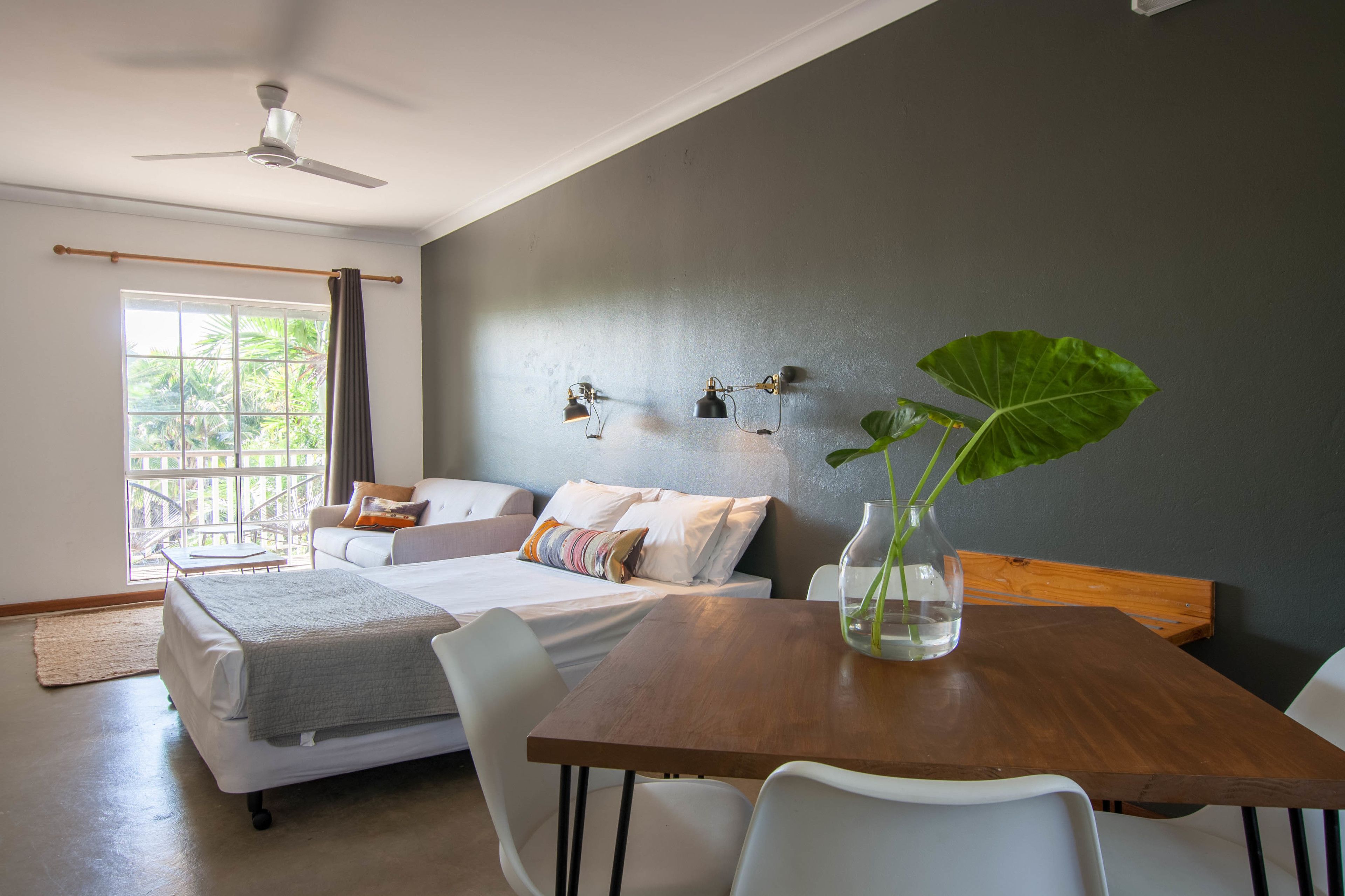 A modern bedroom with a bed, bedside table, and a potted plant.