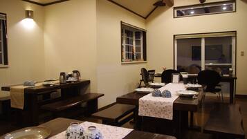 A dining area with wooden tables and benches, a small window, and a wall-mounted light fixture.