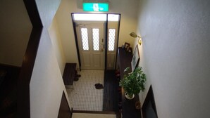A hotel entrance with a tiled floor, a bench, a plant, and a doormat with the hotel's name. - Sunny Side Hut (Hakuba)