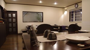 A dining area with a wooden table, chairs, and a clock on the wall. - Sunny Side Hut (Hakuba)