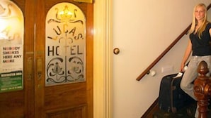 A staircase with a wooden handrail and a sign for 'Hotel' with a logo. - Lucas Hotel (Latrobe)