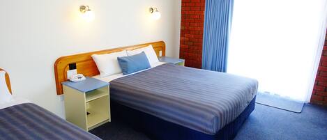 Una habitación de hotel con una cama, mesitas de noche y una pared de ladrillo.
