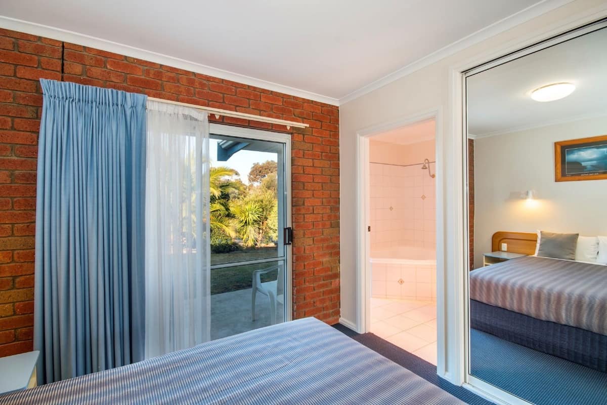 A room with a bed, a sliding glass door to a balcony, and a shower area.