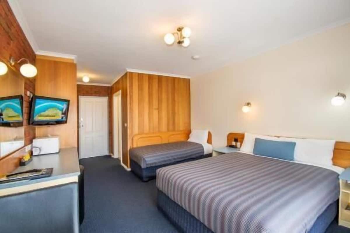 A hotel room with two beds, a desk, and a TV.