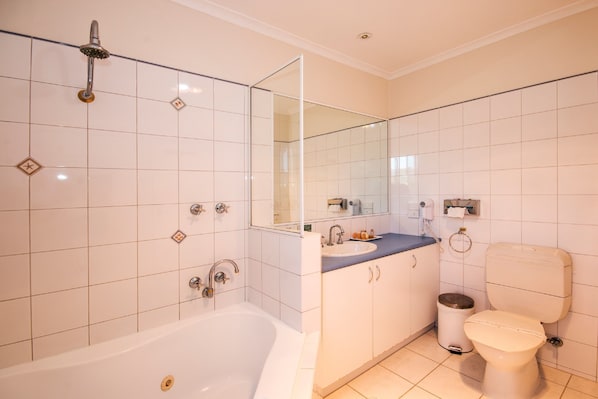 A modern bathroom with a bathtub, a toilet, and a sink. - Torquay Tropicana Motel (Torquay)