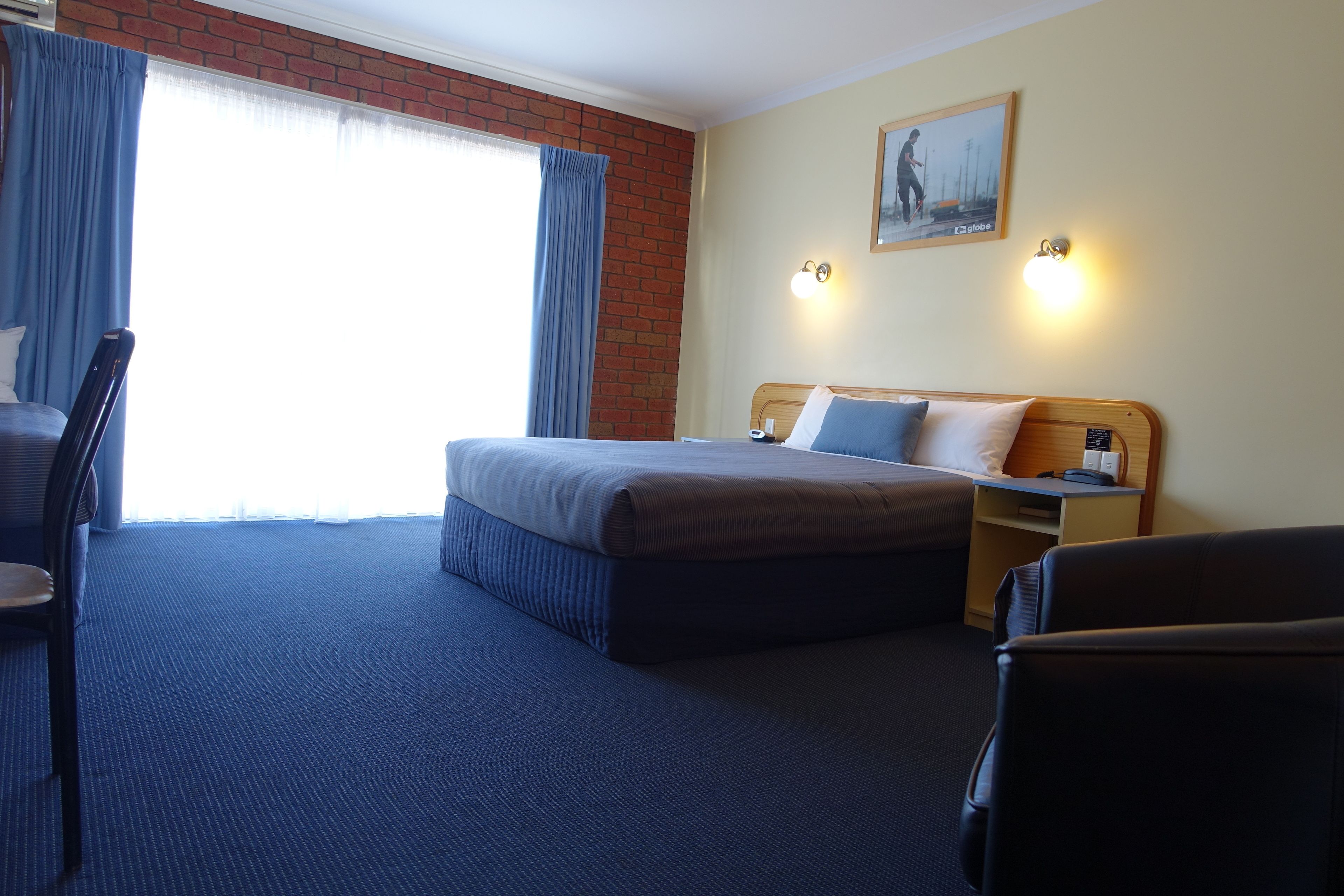 Une chambre d’hôtel avec un grand lit, un bureau, une chaise et une fenêtre avec des rideaux.