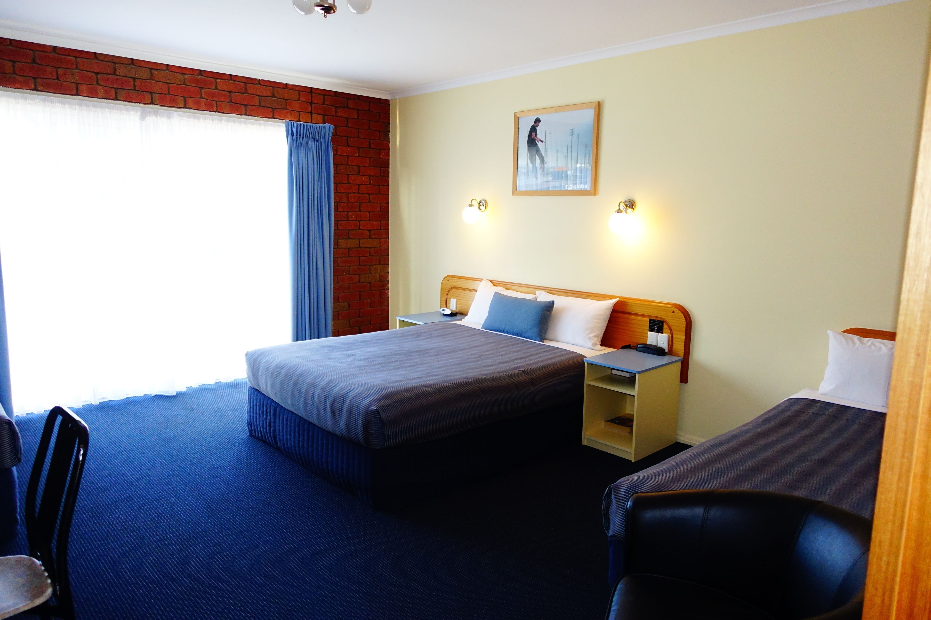 A hotel room with a large bed, a smaller bed, a desk, and a chair.