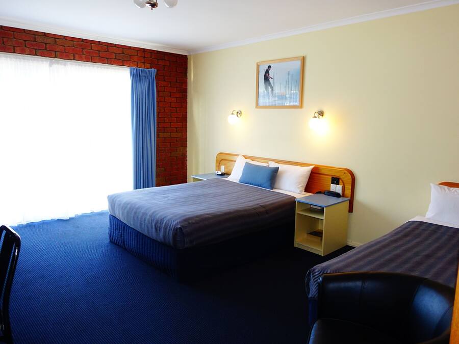 A hotel room with a large bed, a smaller bed, a desk, and a chair.