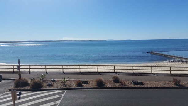 A coastal road with a beach and a pier. - Twenty Two North (Forster)