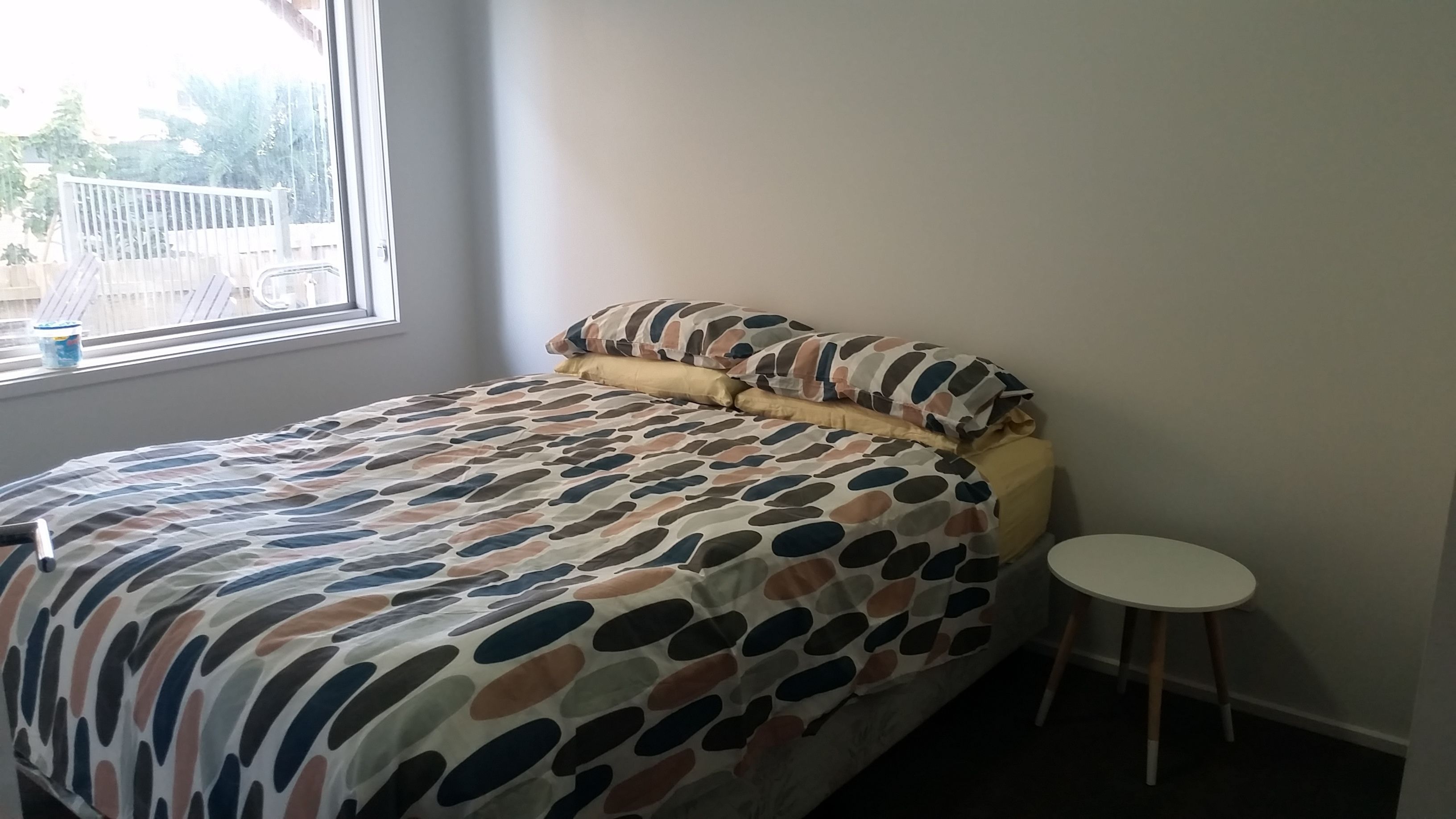 A bedroom with a bed, a small round table, and a window with a view of the outside.
