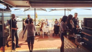 An outdoor seating area with tables and umbrellas, overlooking a body of water. - Twenty Two North (Forster)
