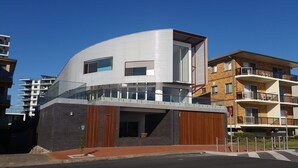 A modern multi-story building with a curved facade, large windows, and a balcony. - Twenty Two North (Forster)