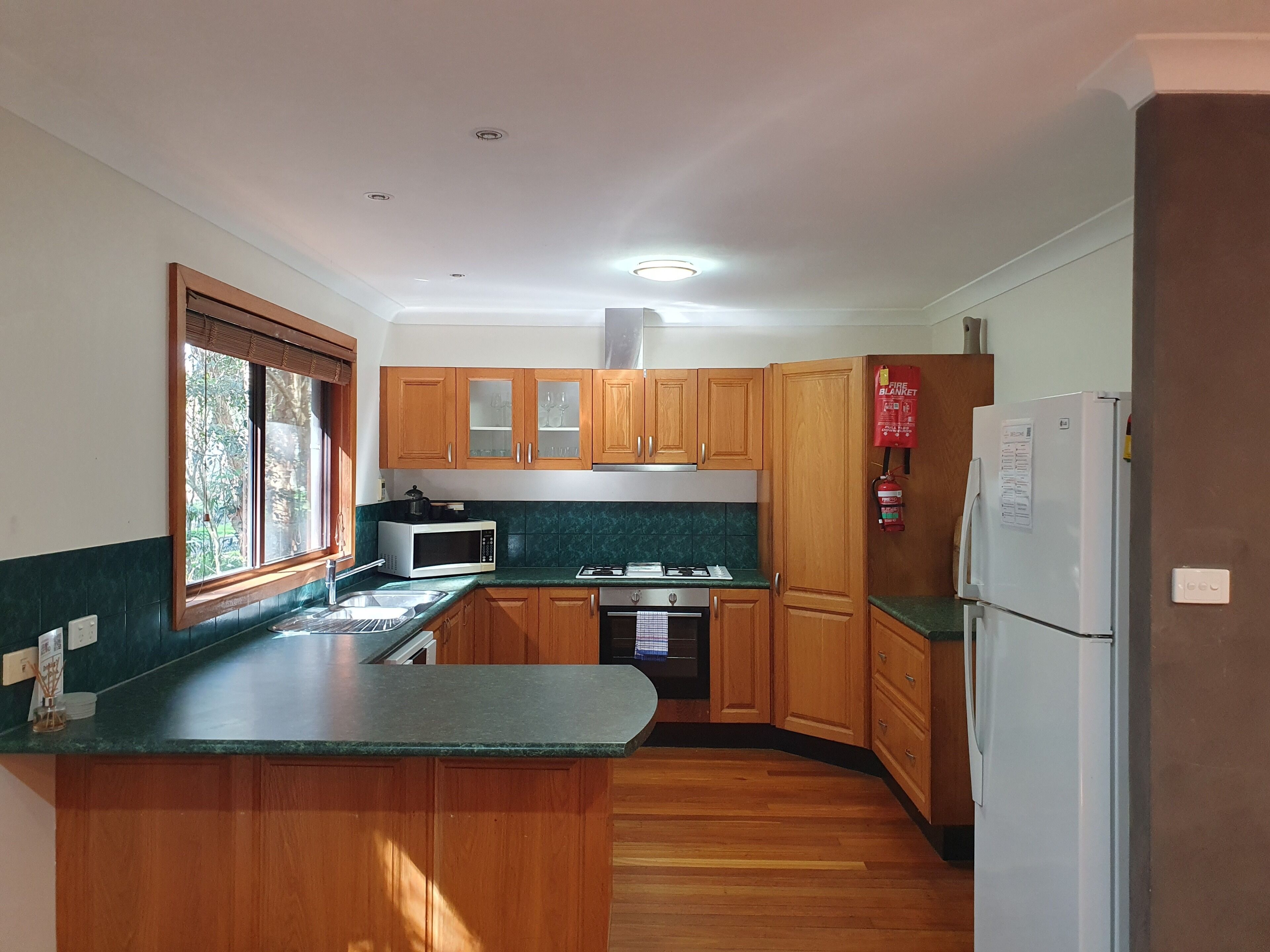 A compact kitchen with wooden cabinets, a microwave, a stove, and a refrigerator.