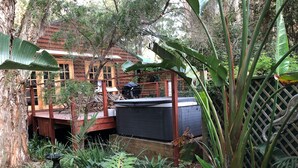 A wooden deck leading to a house labeled "Beach House," surrounded by lush greenery and a wooden fence. - Wanderers Retreat Port Stephens (Boat Harbour)