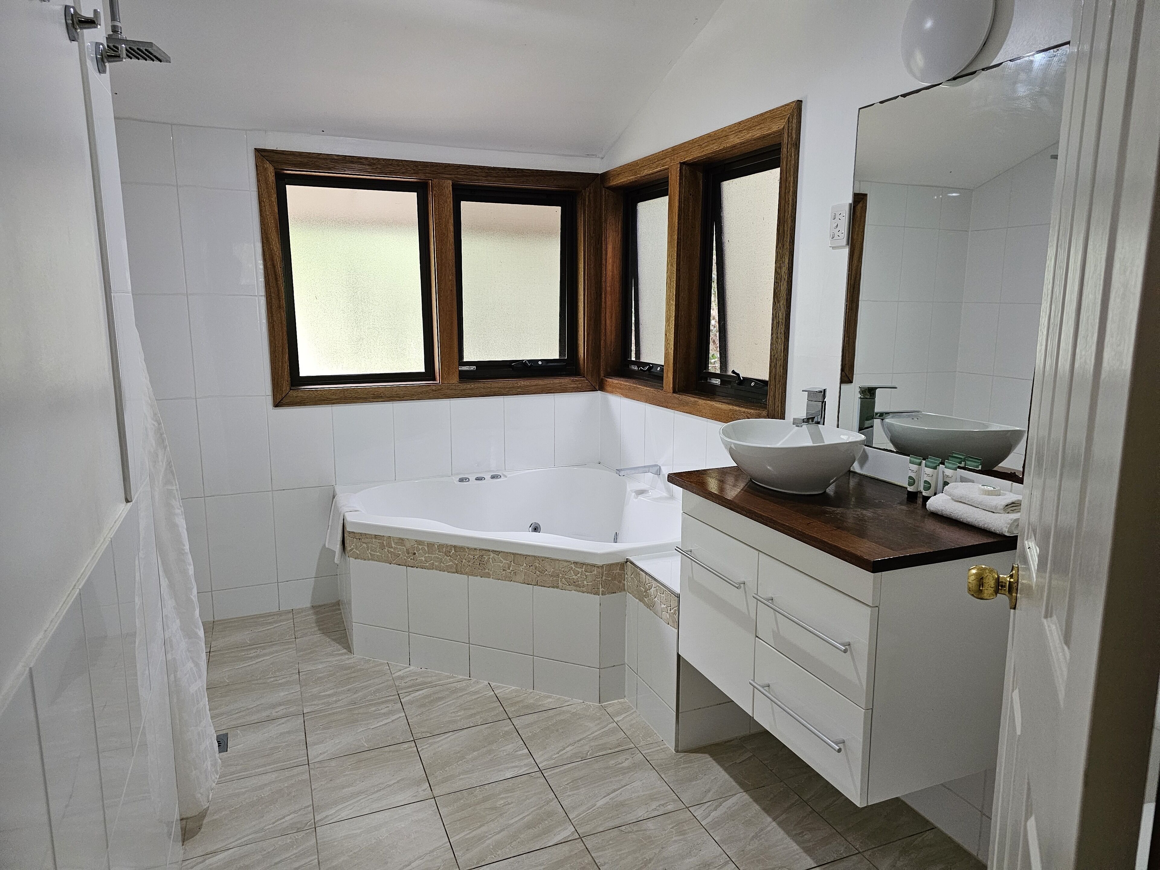 A bathroom with a bathtub, a sink with a large bowl, and a vanity with drawers.