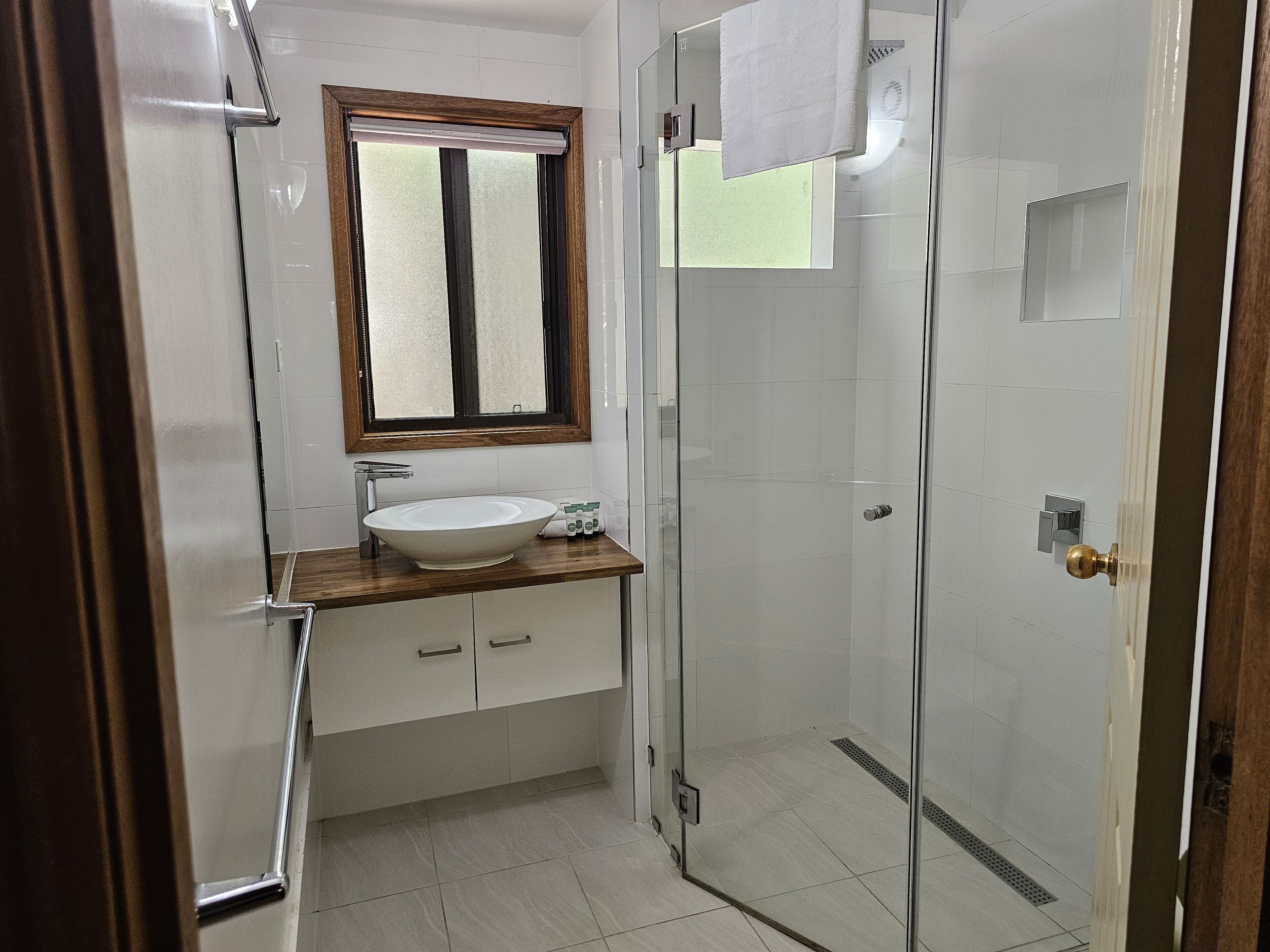 A modern bathroom with a glass-enclosed shower, a white sink, and a wooden countertop.